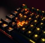 Close-up of a backlit mechanical keyboard with orange LEDs; a keycap is removed, exposing the orange switch underneath.
