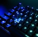 Close-up of a blue-lit mechanical gaming keyboard, focusing on the WASD cluster and surrounding keys.