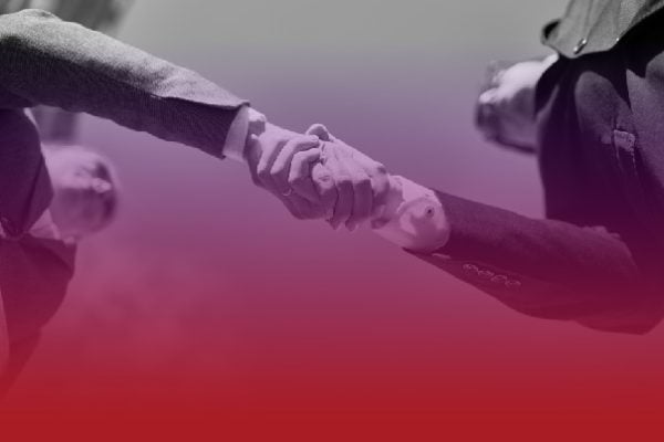 Two businesspeople shake hands, signaling an agreement or partnership.