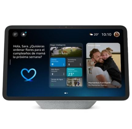 Smart home display showing a Spanish greeting on the left, blue heart icon, widget cards in the center, and a family photo on the right.