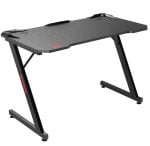 Carbon-fiber textured gaming desk with black angled legs and cable clips on the desktop.
