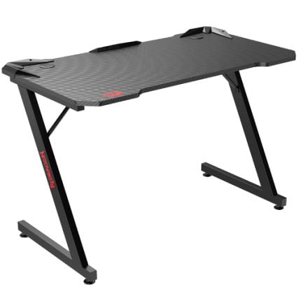 Carbon-fiber textured gaming desk with black angled legs and cable clips on the desktop.