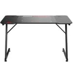 Black carbon-fiber style gaming desk with two metal legs and cross supports, featuring cable holes on the top surface