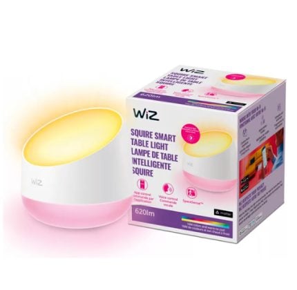 WiZ Squire Smart Table Light with a white base and pink bottom, glowing warm yellow light, shown beside its purple-and-white packaging box.