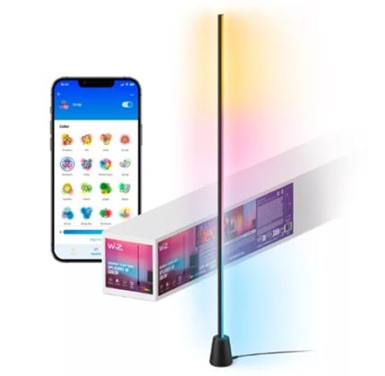 Tall color-changing LED light stick with a base, glowing blue, pink, and yellow light; shown beside a boxed product and a smartphone displaying a colorful emoji app, suggesting app-controlled lighting