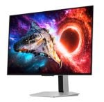 Ultrawide computer monitor on a stand displaying a vibrant space scene with a spaceship near a bright red-black hole.